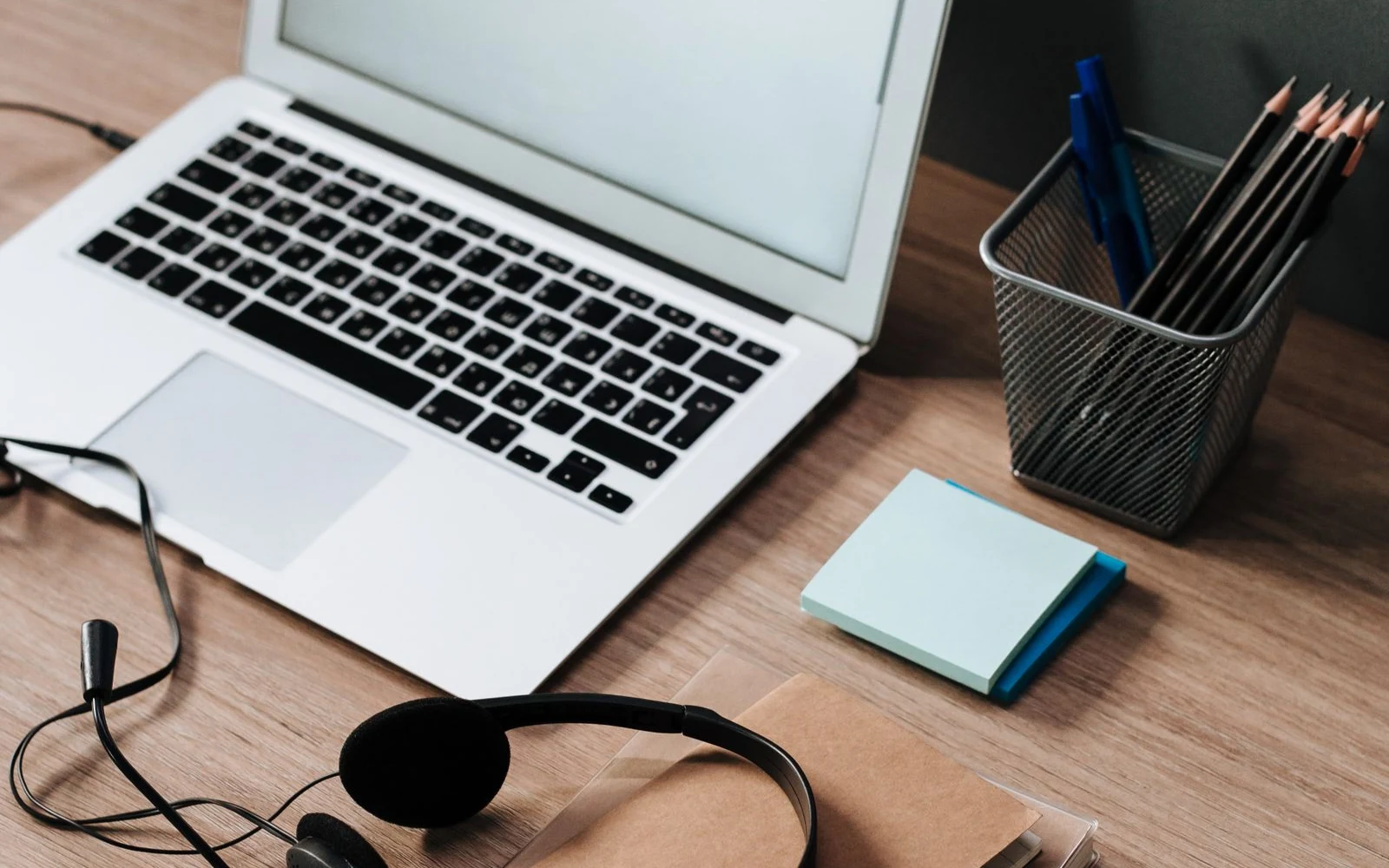 Laptop, headphones and stationery on a wooden work desk